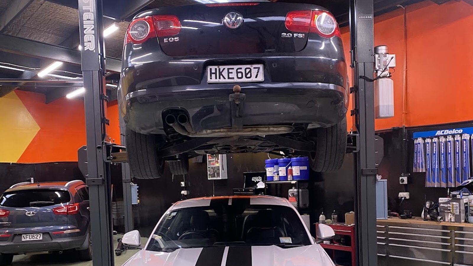 A car up on a hoist in a South End Motors workshop, beside a shelf of ACDelco parts